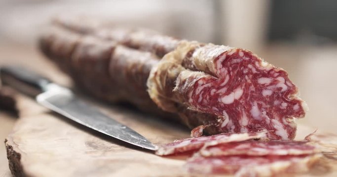 slide sliced dried italian salami on olive board