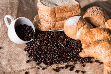 Bread and Croissant on the sackcloth with empty coffee cup and coffee beans.