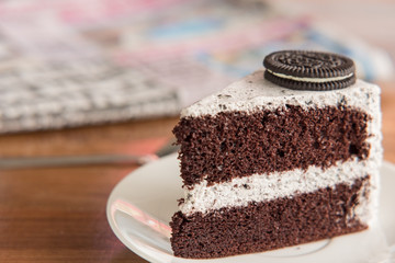 Chocolate Cake with oreo and whipped cream on white plate and wood table has ready to served.