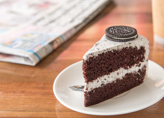 Chocolate Cake with oreo and whipped cream on white plate and wood table has ready to served.