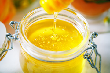 Tasty and healthy honey on white wooden table with flowers of chamomile.
