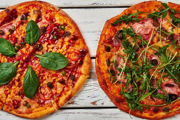 Two baked pizzas, wooden background.