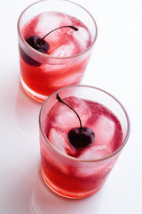 Red drink with a cherry in a glass with ice. © ytochka89