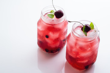 Two glass mugs with a red drink and ice.