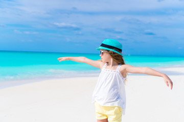 Fototapeta na wymiar Portrait of adorable little girl in hat on white sandy beach