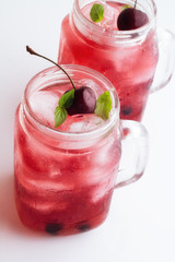 Mugs with red drink, berries and ice on a white background. © ytochka89