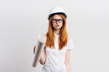 Beautiful young woman on white isolated background holds blueprints, engineer