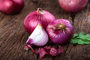 Close up of the  sliced red onion and whole bulb onion on a wooden background