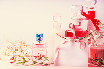 Various cosmetic products bottles and jars with flowers and  empty paper card with ribbon for Invitation, coupon, discount and sale, front view.  Beauty, skin and hair care concept