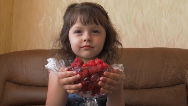 Child with raspberries. A little girl is holding raspberries in her hands.