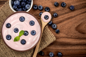 close up  pink creamy homemade blueberries fruit yogurt with fresh green mint leaf on wooden table background , top view or overhead shot