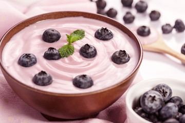 close up the pink creamy homemade blueberries fruit yogurt with fresh green mint leaf on wooden table background
