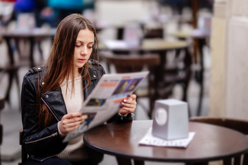 Girl sit at the table and read magazine