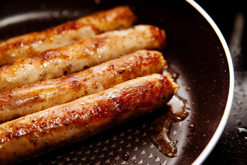 Sausages fried in a frying pan.