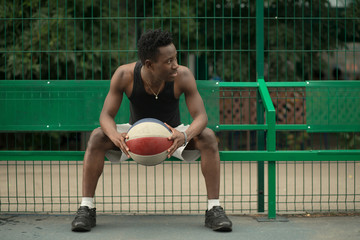 Portrait of african american man sitting on basketball court