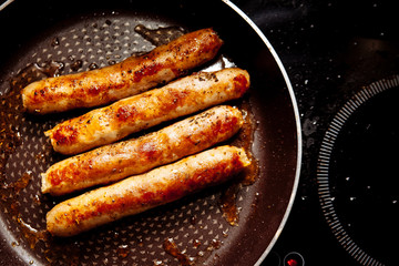 Sausages fried in a frying pan.