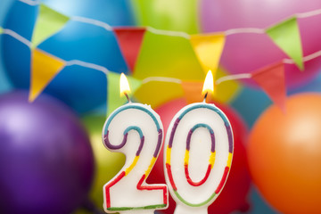 Happy Birthday number 20 celebration candle with colorful balloons and bunting