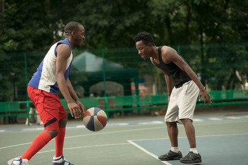 Naklejka premium African american man friends playing on basketball court. Real authentic activity.