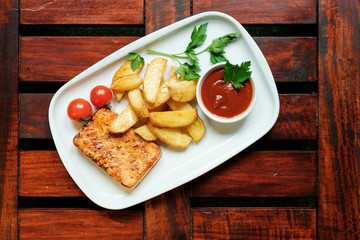 Vegetarian dinner. Fried tofu with spices, potatoes with fresh tomatoes. On a white plate, wooden background.