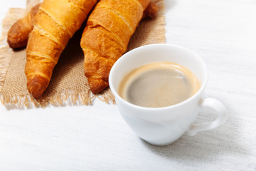 Croissants with coffee on a white table.