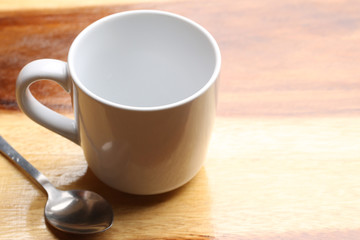 white cup and spoon on wood floor