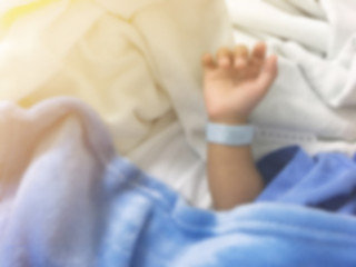 Obraz na płótnie Canvas Blurry background of illness hand kid with name tag bracelets in hospital