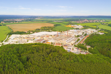 Fototapeta na wymiar Aerial view of factory plant producing ceramic tiles from raw kaolin material. Top view of industrial area in countryside. Large manufacturing plant in landscape.