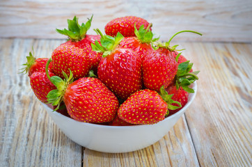Ripe red beautiful juicy bright appetizing strawberry berries. Red strawberries on a light wooden table.