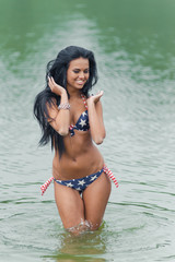 Young beautiful black-haired woman posing on the beach in the water