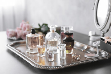 Metal tray with bottles of perfume on table