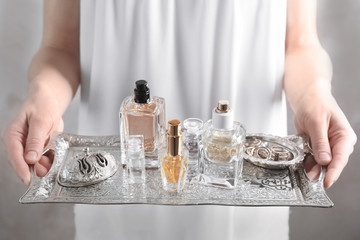 Woman holding metal tray with bottles of perfume