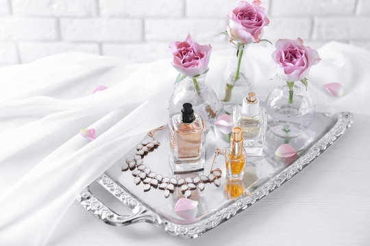 Metal tray with bottles of perfume on table