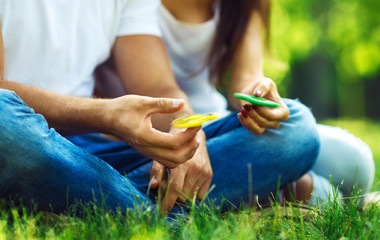 Young girl and boy playing with a fidget spinners in the park. stress relieving toy. Sunny summer...