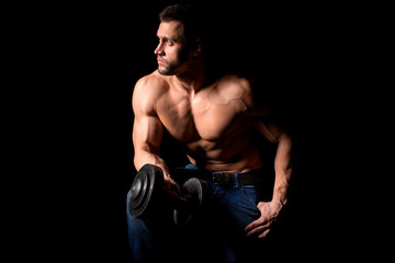 Fototapeta na wymiar Strong man with muscular body working out. Weight exercise with dumbbell on black background.
