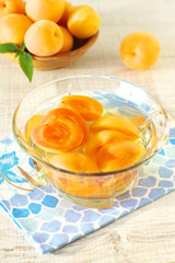 Canned apricots  in glass bowl and fresh apricots with leaves