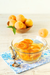 Canned apricots  in glass bowl and fresh apricots with leaves