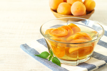 Canned apricots  in glass bowl and fresh apricots with leaves