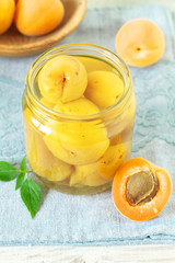 Canned apricots  in glass jar and fresh apricots with leaves