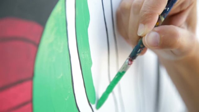 Mani di una pittrice con il pennello stanno dipingendo una parete colorata