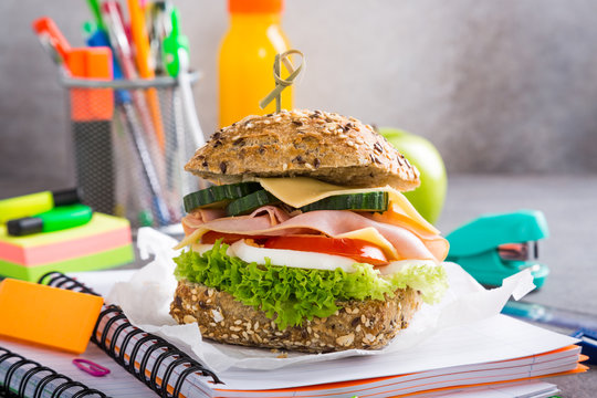 Healthy lunch for school with sandwich, fresh apple and orange juice. Assorted colorful school supplies. Copy space.