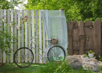 Bicycles in the garden on the background of a tree fence