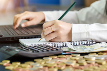 Close up left hand female with pencil writing on the book and right hand using notebook. Calculation at home