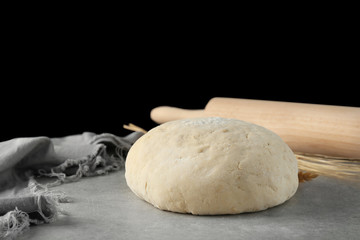 Ball of raw dough on grey table against black background