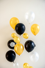 Many bright yellow white and black balloons isolated on backdrop.