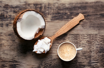 Cup of tasty coconut coffee and spoon with butter on wooden table