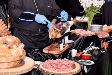 Italian Chef cutting Parma raw ham at event or wedding party buffet