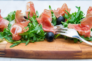 chopping board with aragula and raw ham