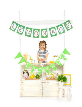 Cute little girl selling lemonade at counter on white background