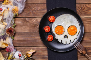 Fried eggs in the shape of a skull and fresh tomatoes. Breakfast in Halloween decorations.