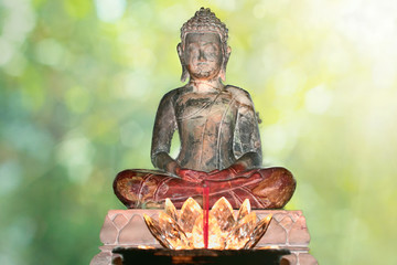 A Buddha statue with a red glowing candle